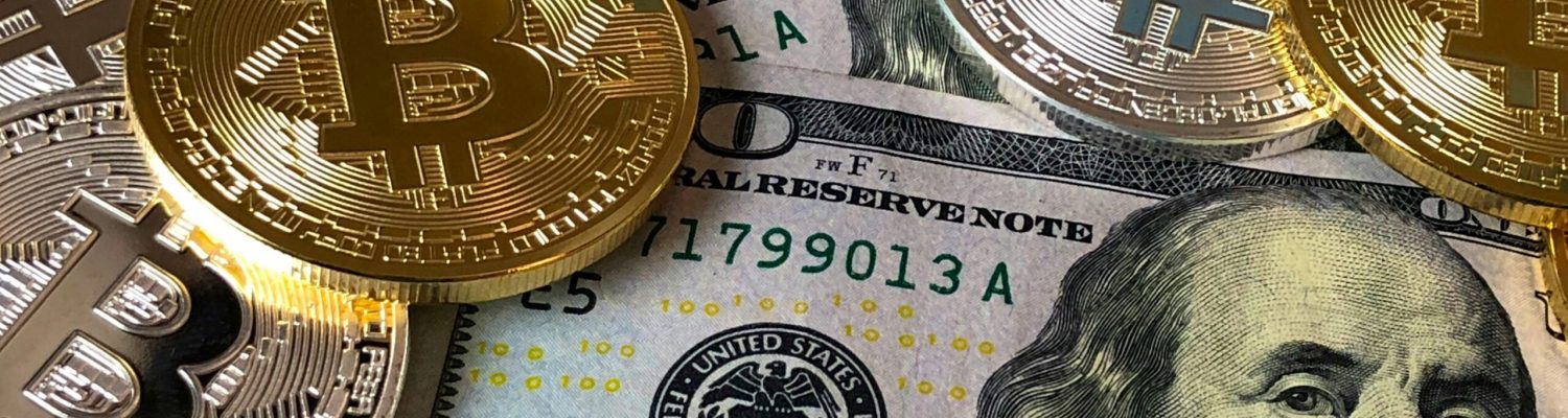 A close-up photo depicting Bitcoin coins on top of US dollar bills, symbolizing finance and cryptocurrency.